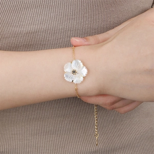 Detail of white shell flower bracelet in gold finish worn on wrist with extender chain