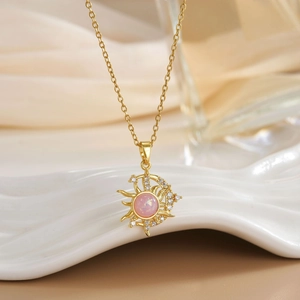 Macro detail of sun and moon gold pendant with pink opal and zircon on silk