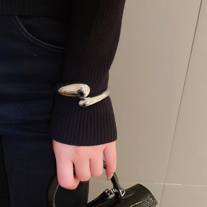 Artistic silver teardrop cuff bracelet styled over a black knit sleeve for a modern look