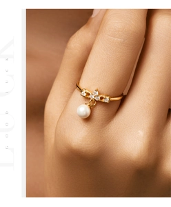 Detail of a gold pendant ring with a bow design, diamonds and a lustrous white pearl