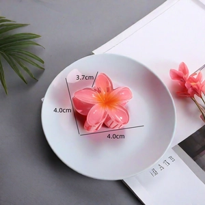 Detail view showing a 4cm pink gradient flower hair claw clip on a stylish white plate