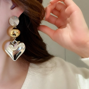 Detail view of large heart drop earrings with gold textured disc and silver pendant