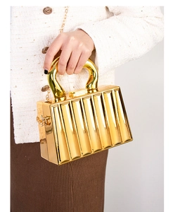 Primer plano de bolso acrílico dorado a rayas con asa metálica y cadena en modelo