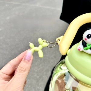 Detail of a light green balloon dog keychain charm on a matching large water bottle