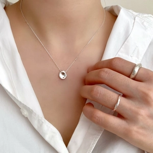 Detail of 925 sterling silver irregular pendant necklace and minimalist rings on a model