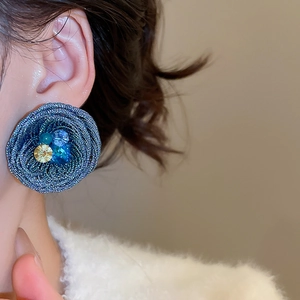 Close-up of woven dark blue flower earring with colorful crystals on model ear