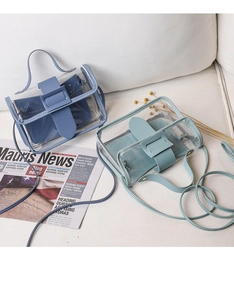 Detail view of mini transparent PVC crossbody bags in blue and green on a sofa