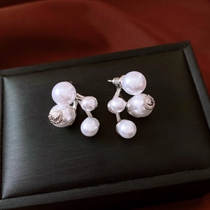 Detail of cluster pearl earrings with relief metal medallion on elegant silk background