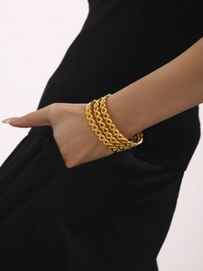 Detail of a 18K gold plated hollow heart-shaped bracelet worn by a model on dark background
