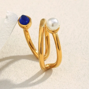 Macro view of gold spiral ring with blue gemstone and white pearl on stone