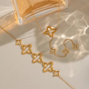 Elegant gold hollow clover pendant necklace and bracelet set on a soft background