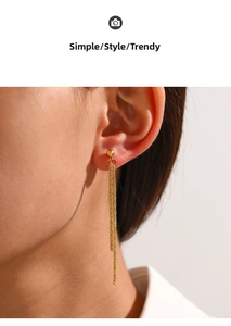 Detail of gold tassel earrings with metallic chain fringe and polished ball stud on a model