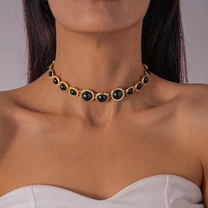Detail of vintage gold choker necklace featuring oval black resin stones on a model