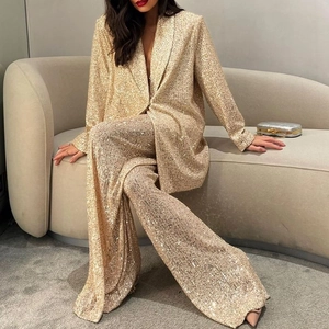Gros plan détaillé des broderies à paillettes dorées sur le blazer et le pantalon large
