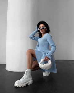 Gros plan du cardigan en maille bleu clair avec rayures verticales et boutons décoratifs