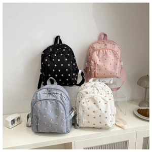 Detailed view of four colorful floral printed backpacks displayed in a cozy lifestyle setting