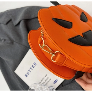 Macro view of pumpkin bag details featuring orange leather texture and gold metal hardware