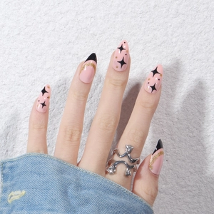 French star glitter press-on nails in pink with gold accents and black star patterns