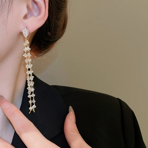 Macro detail of 18k gold plated long tassel earrings with sparkling teardrop zircon stones