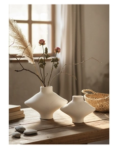 Gros plan de vases en céramique blanc mat avec textures artisanales sur table en bois