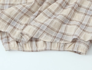 Detailed close-up of plaid fabric texture with elasticated hem on a cropped top