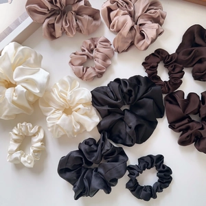 Detailed view of oversized silk scrunchies in cream, champagne and brown earth tones