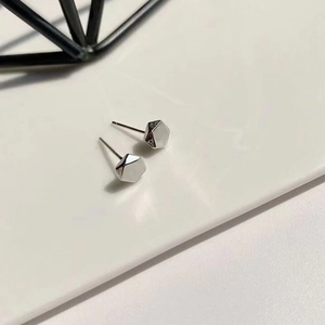 Macro detail of silver geometric hexagonal punk stud earrings with polished metallic finish