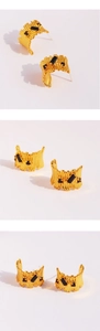 Macro detail of gold C-shape earrings featuring wavy texture and black zircon stones