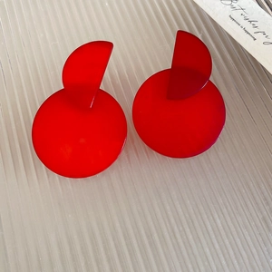 Detailed view of red geometric resin pendant earrings on a white textured background