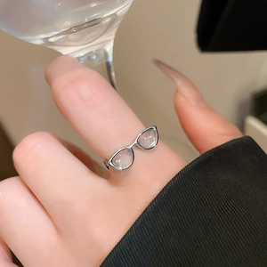 Detail of silver-tone y2k glasses shaped ring with translucent resin lenses on finger