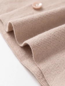 Close-up of beige ribbed knit fabric with a matching button detail on the garment