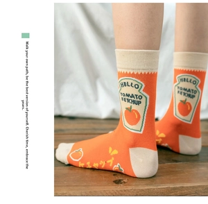 Detail of orange cotton mid-calf socks with creative ketchup illustration and white accents