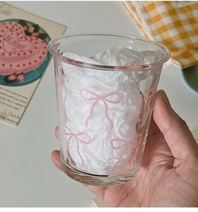 Detail of a transparent glass cup with pink bow patterns in a lifestyle setting