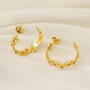 Macro shot of 18K gold plated hollow star earrings on soft silk fabric background