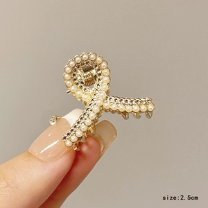 Detail of 2.5cm golden alloy hair claw with white pearls and twisted ribbon design