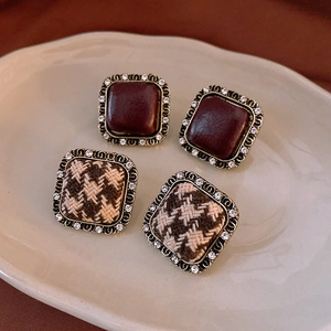 Detail of vintage square earrings with houndstooth fabric and burgundy stone in metallic frame