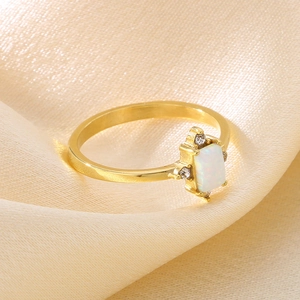 Detail of gold titanium ring with a white opal stone and side diamonds on silk