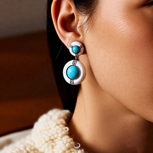 Détail de boucles d'oreilles vintage avec émail blanc, turquoise et cristaux