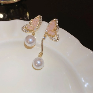 Detail of asymmetric butterfly earrings with pink crystals and white pearls on gold frames