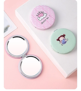 Close-up of portable round compact mirrors showing the dual-sided design and pink crown pattern