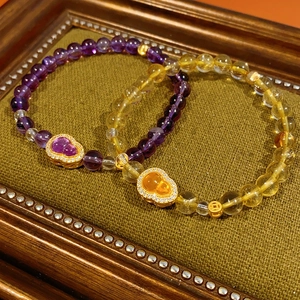 Macro shot of citrine and amethyst bracelets with gold gourd charms on green velvet