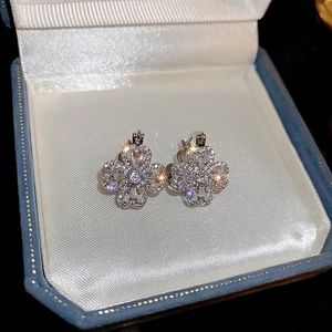 Detailed view of silver clover earrings with sparkling cubic zirconia in jewelry box