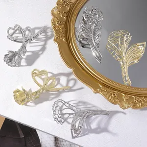 Detailed view of metal rose hair claws in gold and silver finish on mirror background