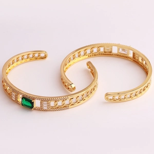 Close-up of gold chain bracelets with emerald and clear rectangle cut zircon stones