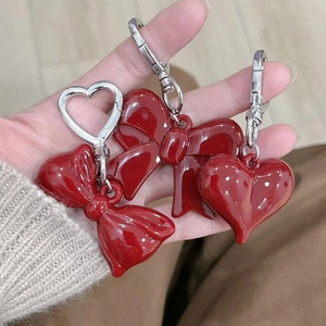 Detail of red acrylic bow and heart charm keychain with silver metal clip on hand