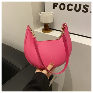 Close-up of pink crescent underarm bag with smooth PU leather and gold-tone hardware