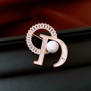 Detailed close-up of 14K gold plated D-letter brooch with pearl, mother of pearl and zircon