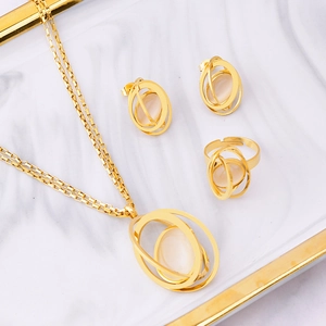 Golden jewelry set with white opal necklace, ring and earrings on marble tray