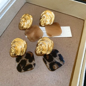 Macro view of gold shell textured metal earrings with square marble and leopard acrylic charms