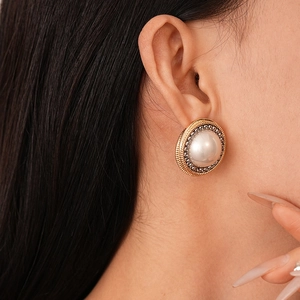 Close-up of vintage mixed-metal chain link earrings with center pearl on a model